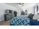 Large main bedroom featuring blue accent wall, wood floors, ceiling fan, dresser, and view to ensuite bath at 209 Hearthstone Reach, Peachtree City, GA 30269