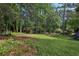 Large backyard with mature trees, green grass, and a storage shed at 5421 Brownlee Rd, Stone Mountain, GA 30087
