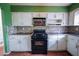A view of the kitchen with black appliances, mosaic backsplash, and white cabinets at 1443 Snapfinger Rd, Decatur, GA 30032