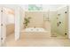 Luxurious bathroom featuring a soaking tub, glass enclosed shower, and neutral tile throughout at 1915 Milfield Cir, Snellville, GA 30078