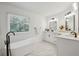 Bright bathroom featuring dual vanity, soaking tub, and window with natural light at 2350 Twelvestones Dr, Roswell, GA 30076