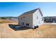 View of the home's backyard featuring a two-story house, lawn, and concrete patio under a bright blue sky at 33 N Village Cir, Rydal, GA 30171