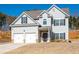 Two-story home featuring a two-car garage, dormers, traditional windows, and a well-maintained lawn at 33 N Village Cir, Rydal, GA 30171