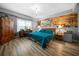 Comfortable bedroom showcasing a wood accent wall, a large window, and wood-look floors at 7401 Cherry Blossom Way, Winston, GA 30187