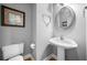 Stylish powder room with pedestal sink, decorative mirror, and grey painted walls at 7401 Cherry Blossom Way, Winston, GA 30187