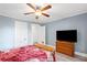 This bedroom features light blue walls, a wooden dresser, ceiling fan, and television at 1591 Jonesboro Se Rd, Atlanta, GA 30315