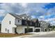 View of townhomes featuring a mix of white and charcoal exteriors, gabled roofs, and single-car garages at 206 Sharon Ln, Loganville, GA 30052