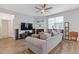 Cozy living room with a fireplace, large windows, ceiling fan, and hardwood floors at 3825 Sycamore Hill Dr, Loganville, GA 30052