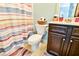 Well-lit bathroom with a toilet, vanity, decorative shower curtain and coordinating rugs at 165 Craines Vw, Covington, GA 30014