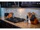 Close-up of a gas cooktop with granite counters, stainless steel appliances, and backsplash at 165 Craines Vw, Covington, GA 30014