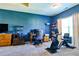 Bedroom featuring blue accent wall, desk area, large window, and exercise bike at 165 Craines Vw, Covington, GA 30014