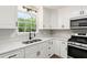 Bright kitchen features white cabinets, stone countertops, stainless steel appliances, and view of backyard trees at 4170 Maroney Mill Rd, Douglasville, GA 30134