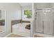 Bright bathroom features a soaking tub under a window and glass-enclosed shower at 7095 Valley Landing Ct, Cumming, GA 30041