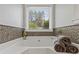Luxurious bathtub showcasing mosaic tile and serene outdoor views at 7095 Valley Landing Ct, Cumming, GA 30041