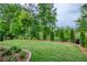 Manicured backyard with lush lawn, landscaping, and mature trees at 714 Chipping Sparrow St, Canton, GA 30115