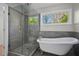 Modern bathroom featuring a glass enclosed shower, garden tub, and window at 194 Beaverwood Ct, Lawrenceville, GA 30044