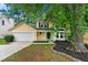 Charming yellow two-story home with a well-maintained yard and attached garage and a black front door at 194 Beaverwood Ct, Lawrenceville, GA 30044
