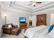 Spacious bedroom with a tray ceiling, wooden furniture, and a comfortable seating area for relaxation at 2470 Crimson Downs Dr, Cumming, GA 30040