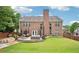 Large backyard with a stone patio, seating, a well-kept lawn, and a classic brick house facade at 4590 Hastings Dr, Cumming, GA 30041