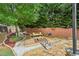 Landscaped backyard with stone pathways, a fire pit, mature trees, and a charming wooden bridge and fence at 4590 Hastings Dr, Cumming, GA 30041