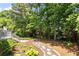 Landscaped backyard with stone path leading to a wooded area and deck at 210 Wentworth Ter, Alpharetta, GA 30022