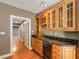 Home bar area with wine rack, wooden cabinets, granite countertop, sink, and beverage cooler at 210 Wentworth Ter, Alpharetta, GA 30022