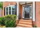 Elegant front entrance features a classic black door with sidelights, brick steps, and manicured landscaping at 210 Wentworth Ter, Alpharetta, GA 30022