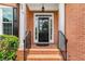Stylish front entry showcasing a black door with glass panels, brick facade, and manicured landscaping at 210 Wentworth Ter, Alpharetta, GA 30022