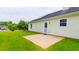 Backyard view featuring a concrete patio, green grass, and siding on the home with solar panels at 213 Whistle Way, Locust Grove, GA 30248