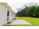 Backyard view featuring a concrete patio, green grass, and lush trees with siding on the home at 213 Whistle Way, Locust Grove, GA 30248
