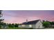 Beautifully maintained home with vinyl siding, a dark roof, solar panel, and manicured lawn under a vibrant purple sunset at 213 Whistle Way, Locust Grove, GA 30248