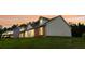 A quaint home featuring brick accents, vinyl siding, and evenly spaced windows against a beautiful orange sunset backdrop at 213 Whistle Way, Locust Grove, GA 30248
