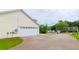 Garage featuring a white door, long driveway, and green yard with trees on a sunny day at 213 Whistle Way, Locust Grove, GA 30248