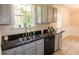 Kitchen view of granite countertop, stainless sink, and black dishwasher in a well-lit space at 213 Whistle Way, Locust Grove, GA 30248