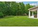 Expansive backyard with lush green grass, mature trees, and covered patio at 2358 Well Springs Dr, Buford, GA 30519