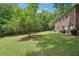 Wide backyard showcases the side of a brick home and lush greenery, creating a serene outdoor space at 3235 Munsey Ct, Cumming, GA 30041