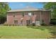 Backyard view of a brick house featuring a manicured lawn, mature trees, and a serene outdoor space at 3235 Munsey Ct, Cumming, GA 30041