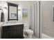 Bathroom with a marble vanity, a dark wood cabinet, decorative mirror and shower with neutral striped curtain at 3235 Munsey Ct, Cumming, GA 30041