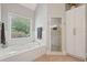 Bright bathroom featuring a jetted tub, storage cabinet, window with blinds, and glass-enclosed shower stall at 3235 Munsey Ct, Cumming, GA 30041