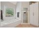 Bright bathroom features a jetted tub beneath a window, accompanied by a separate glass shower and storage cabinet at 3235 Munsey Ct, Cumming, GA 30041