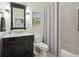 A compact bathroom with a dark wood vanity, decorative mirror, and shower with curtain at 3235 Munsey Ct, Cumming, GA 30041