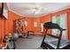 Well-equipped exercise room with orange walls, mirrored tv, ceiling fan, and a variety of equipment at 3235 Munsey Ct, Cumming, GA 30041