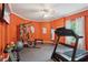 Orange walled fitness room with rubber flooring, weight-lifting machine, treadmill, and heavy bag at 3235 Munsey Ct, Cumming, GA 30041