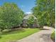 Charming home exterior featuring a curved driveway, lush landscaping, and mature trees for added privacy at 3235 Munsey Ct, Cumming, GA 30041