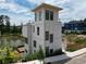 Modern home exterior with a rooftop balcony overlooking a serene lake and well-manicured lawn at 1230 Mado Loop, Chattahoochee Hills, GA 30268