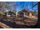 View of the home's backyard featuring a porch, brick facade, storage building and trees with fallen leaves at 341 Little John Nw Dr, Lilburn, GA 30047