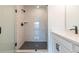 Bright bathroom featuring glass shower with white brick surround, black fixtures, and vanity with solid surface counters at 4818 Floydwood Ln, Mableton, GA 30126