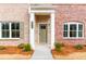 Charming brick home entrance with a well-manicured lawn, white columns, and a stylish front door at 4818 Floydwood Ln, Mableton, GA 30126