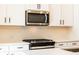 Close-up of a kitchen featuring white cabinets, a stainless steel microwave and a modern stove at 4818 Floydwood Ln, Mableton, GA 30126