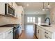 Bright, modern kitchen boasts stainless steel appliances, white cabinets, and sleek countertops overlooking an open living space at 4818 Floydwood Ln, Mableton, GA 30126
